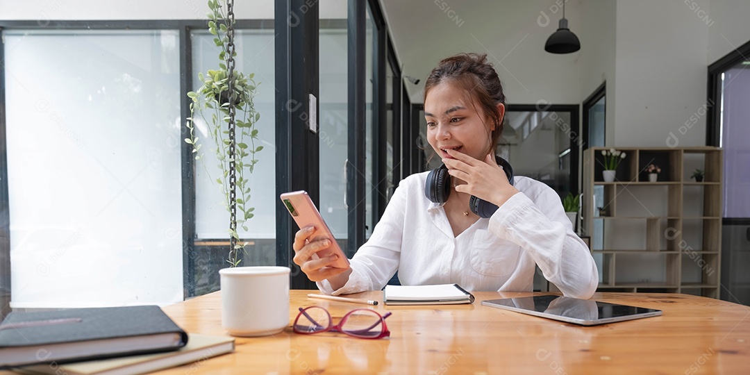 Feliz jovem adolescente asiática sentada em casa segurando o telefone