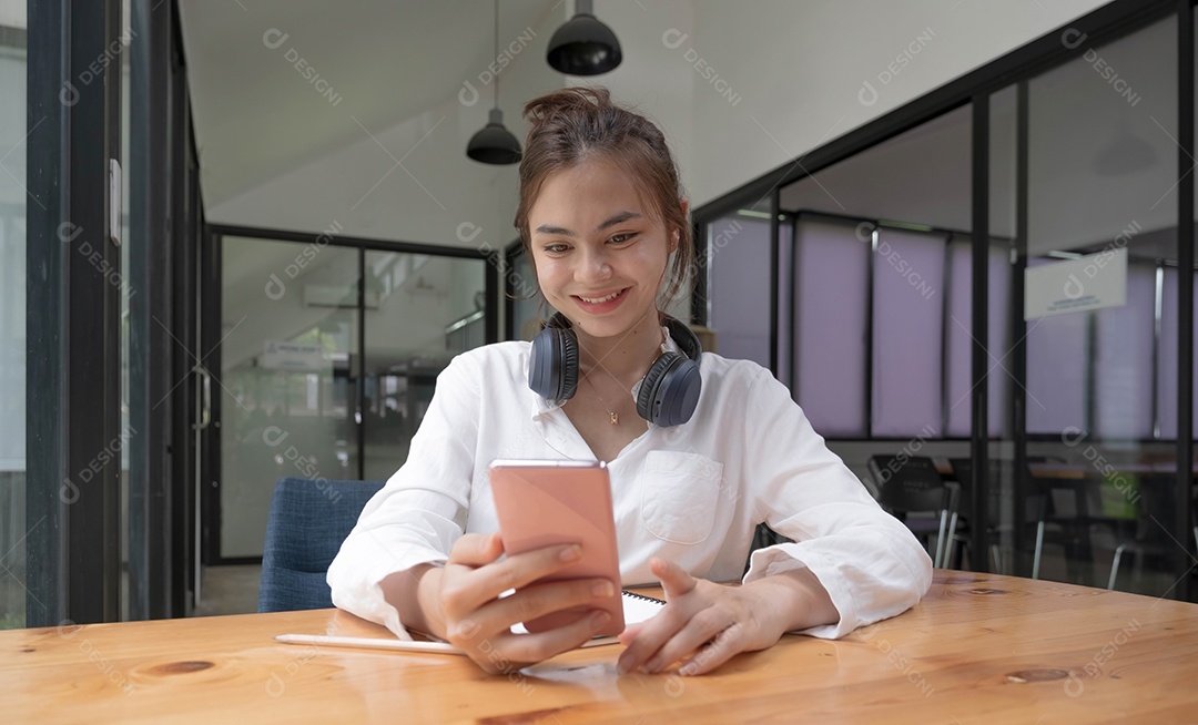 Feliz jovem adolescente asiática sentada em casa segurando o telefone