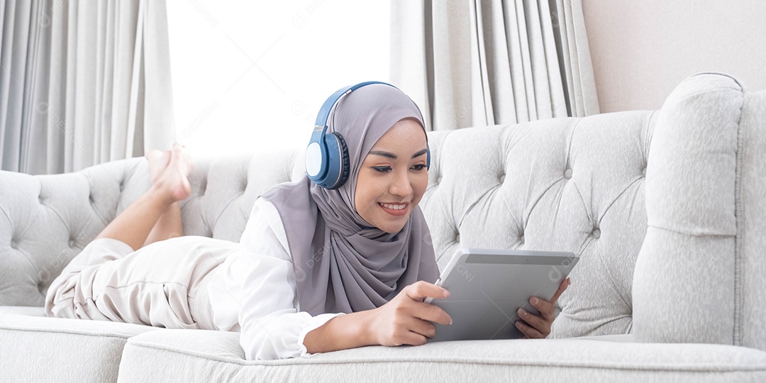 Mulher muçulmana asiática relaxada e feliz com hijab deitado no sofá