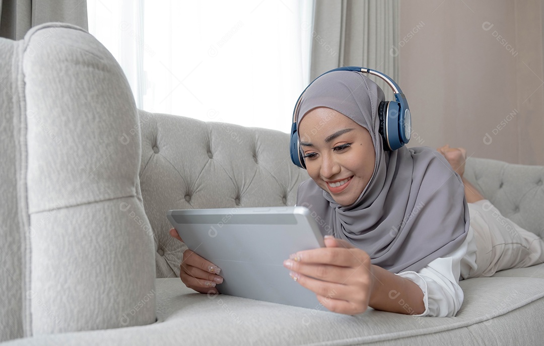 Mulher muçulmana asiática relaxada e feliz com hijab deitado no sofá