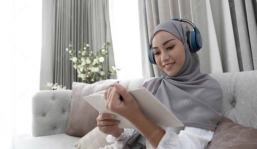 Encantadora jovem muçulmana asiática usando hijab e fones de ouvido