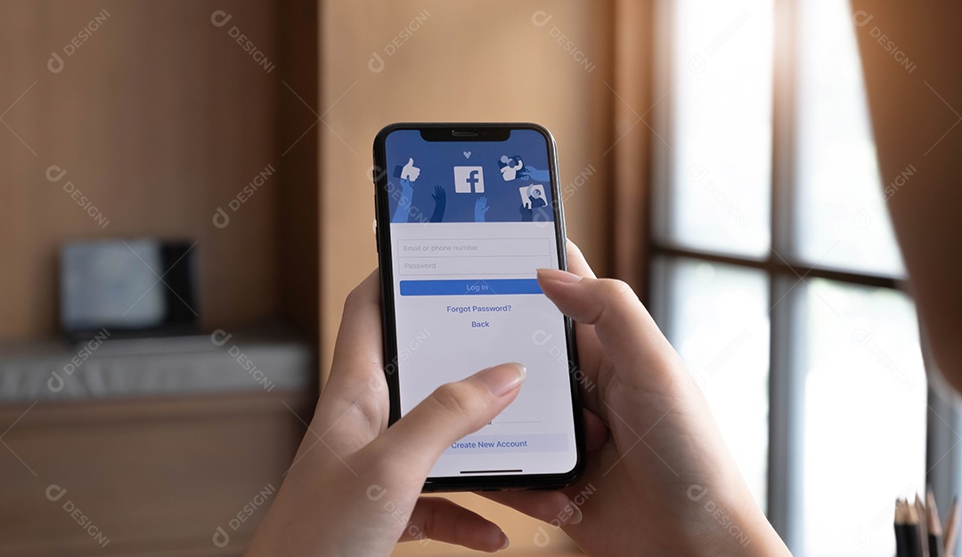 Mulher segurando um iPhone X com serviço social de Internet Facebook na tela.