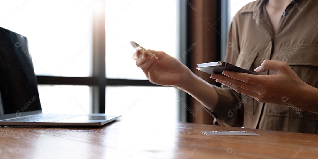 Mãos de mulher segurando um cartão de crédito e usando smartphone