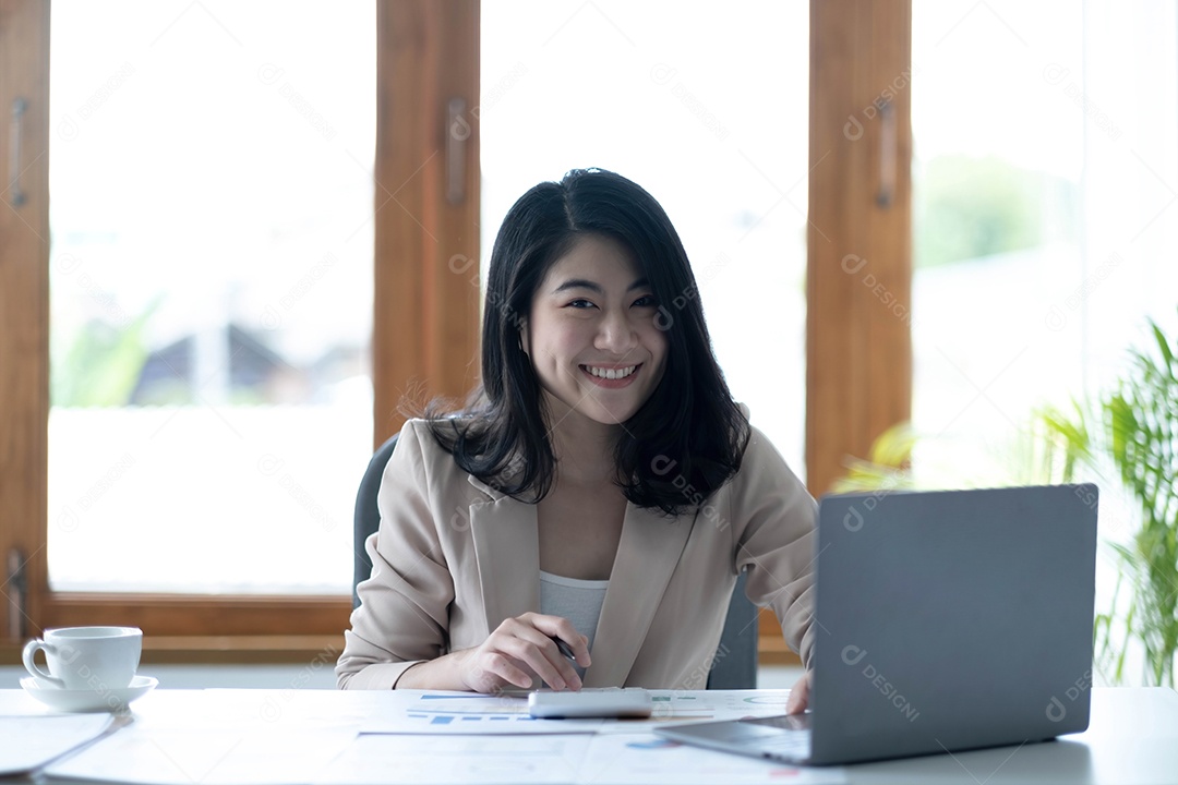 Encantadora mulher asiática trabalhando no escritório usando um laptop