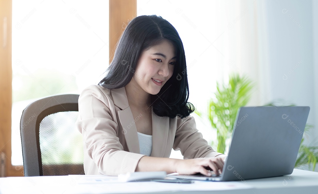 Bela jovem asiática sentada na cafeteria usando o laptop.