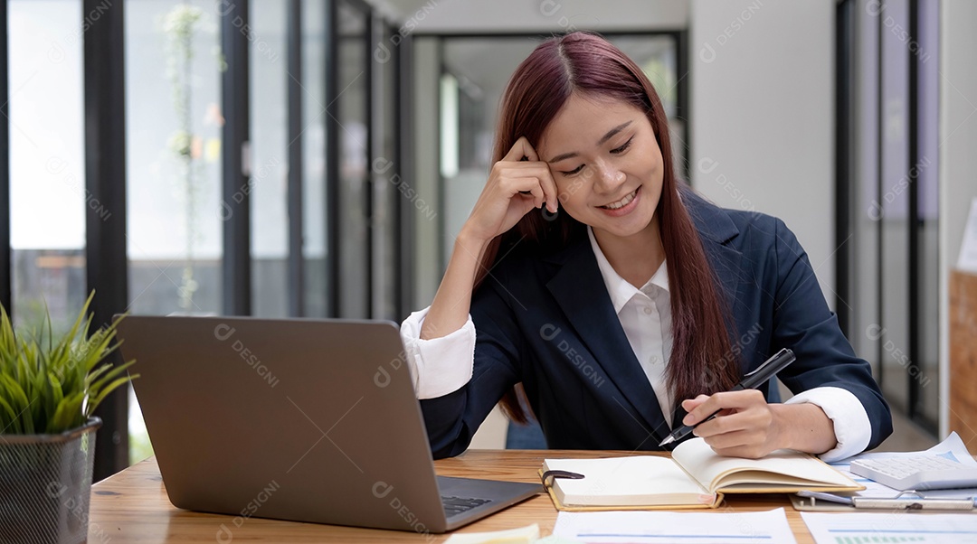 Encantadora empresária asiática sentada trabalhando no laptop no escritório