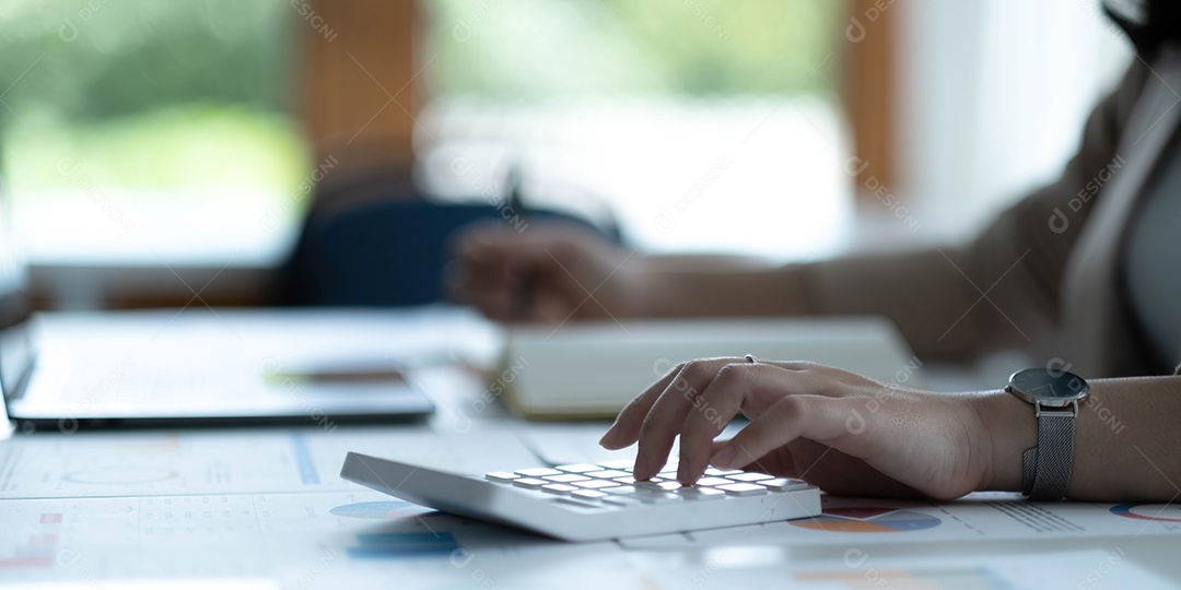 Mão da mulher de negócios usando a calculadora para calcular