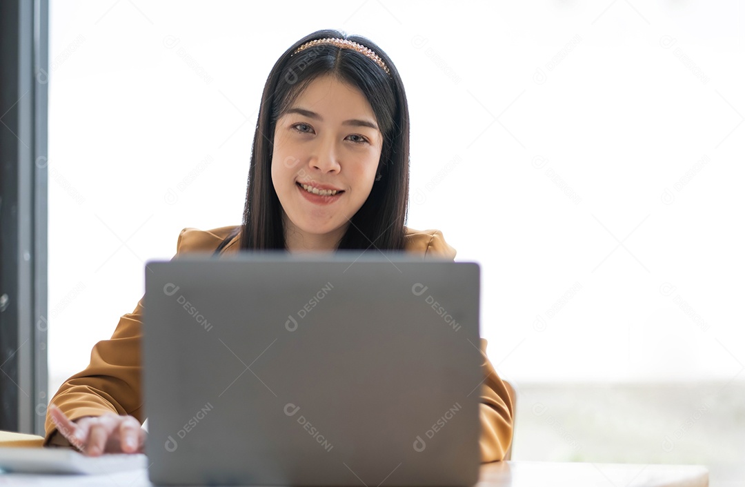 Encantadora mulher asiática trabalhando no escritório usando um laptop