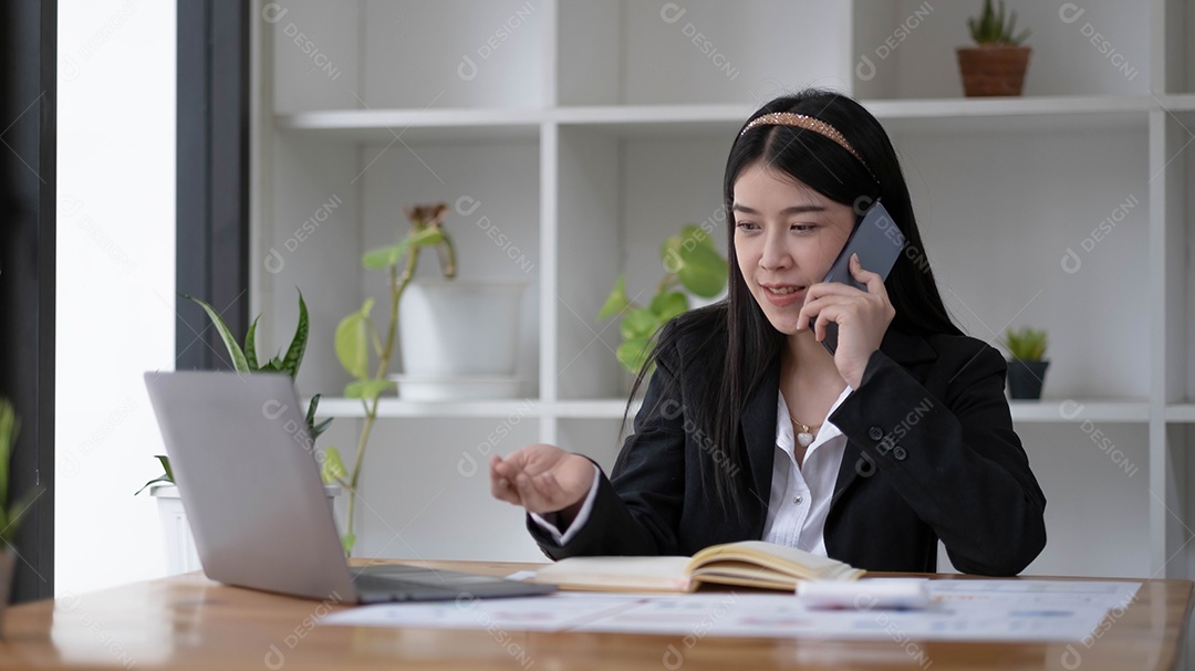 Mulher de negócios asiática falando ao telefone com o cliente