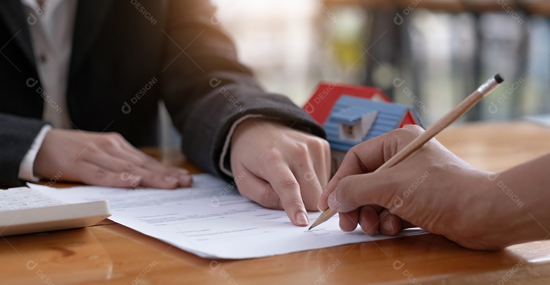 Agente imobiliário e cliente fazem contrato para comprar e vender casa e terreno.