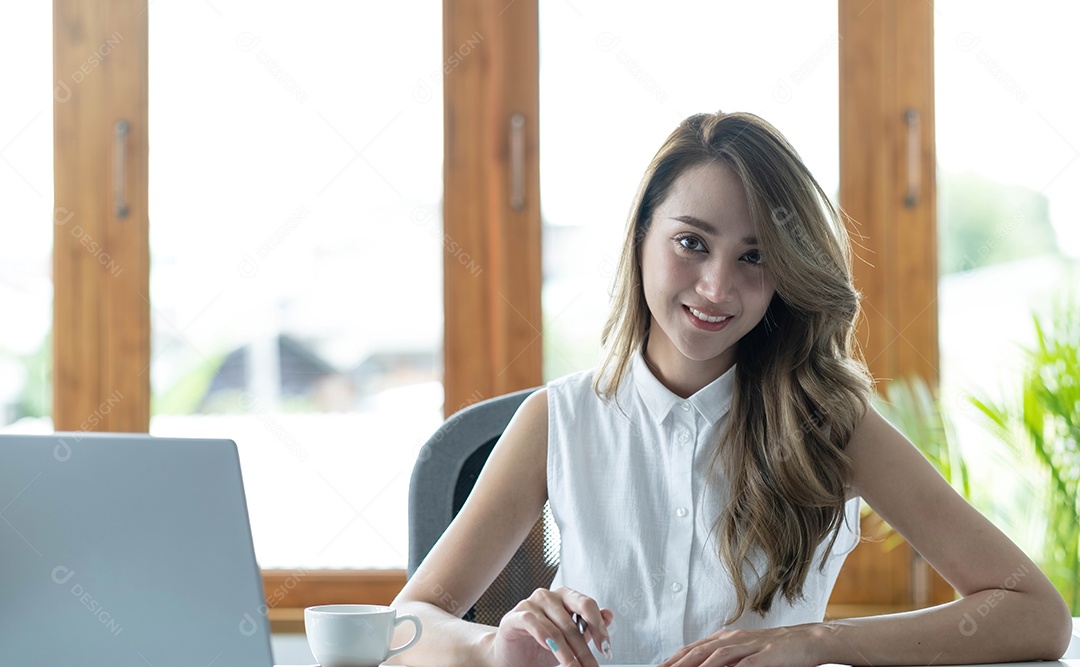 Jovem mulher bonita usando seu laptop enquanto está sentado em uma cadeira
