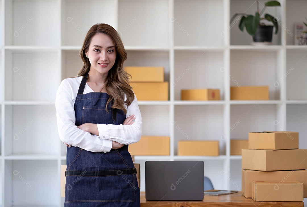 Retrato de uma jovem asiática PME trabalhando com uma caixa em casa