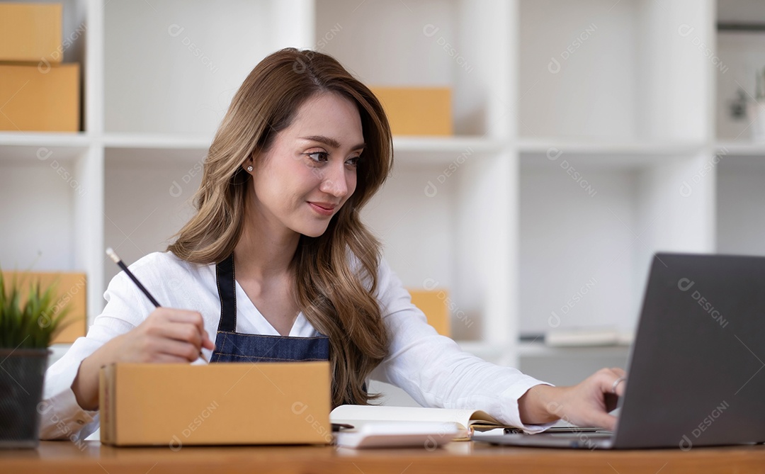 Retrato de uma jovem asiática PME trabalhando com uma caixa em casa