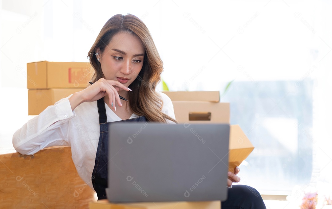 Retrato de uma jovem asiática PME trabalhando com uma caixa em casa