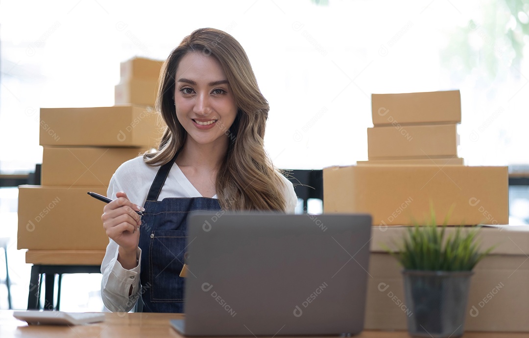 Retrato de uma jovem asiática pequena empresa trabalhando com uma caixa em casa