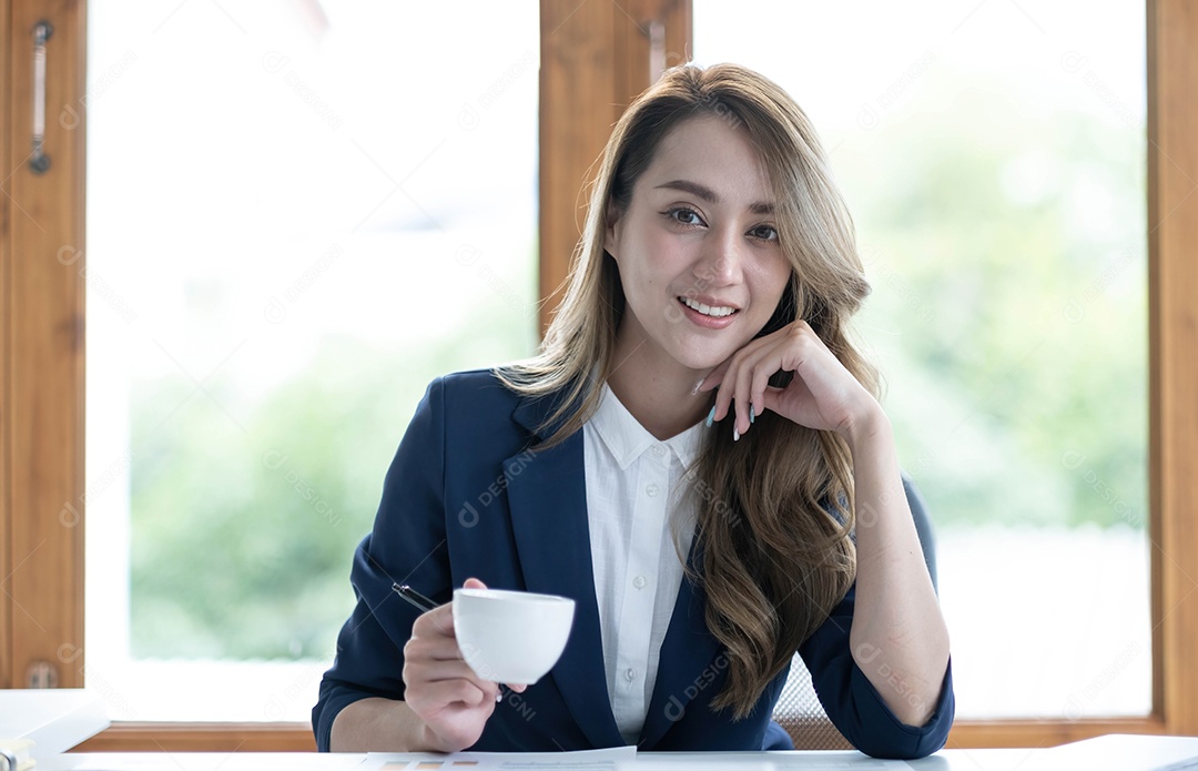 Bela jovem empresária asiática bebendo um café trabalhando