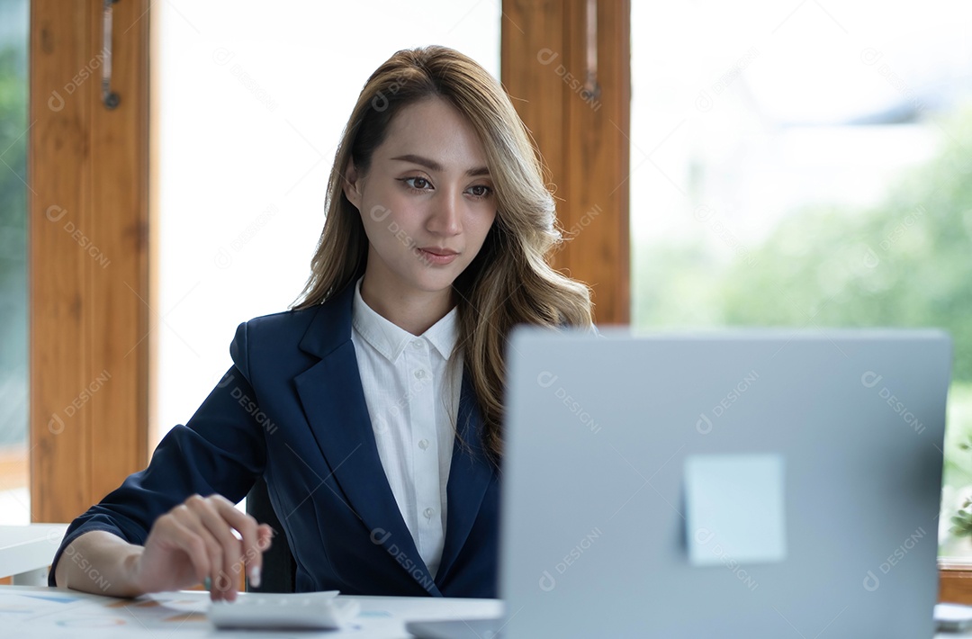 Encantadora empresária asiática sentada trabalhando no laptop no escritório