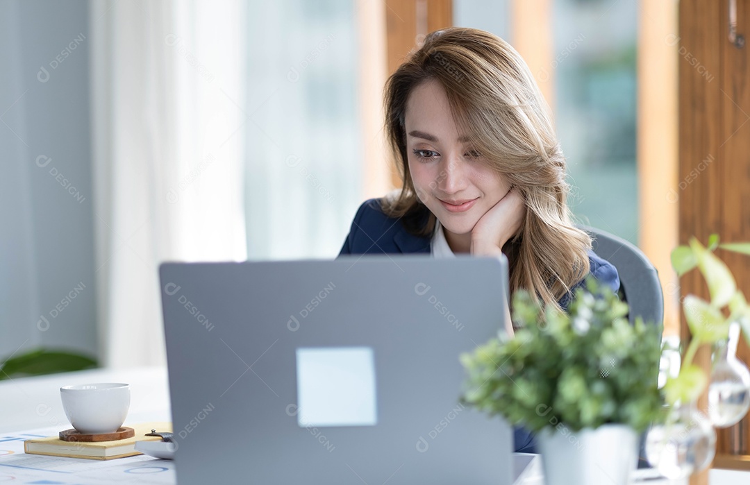 Encantadora empresária asiática sentada trabalhando no laptop no escritório