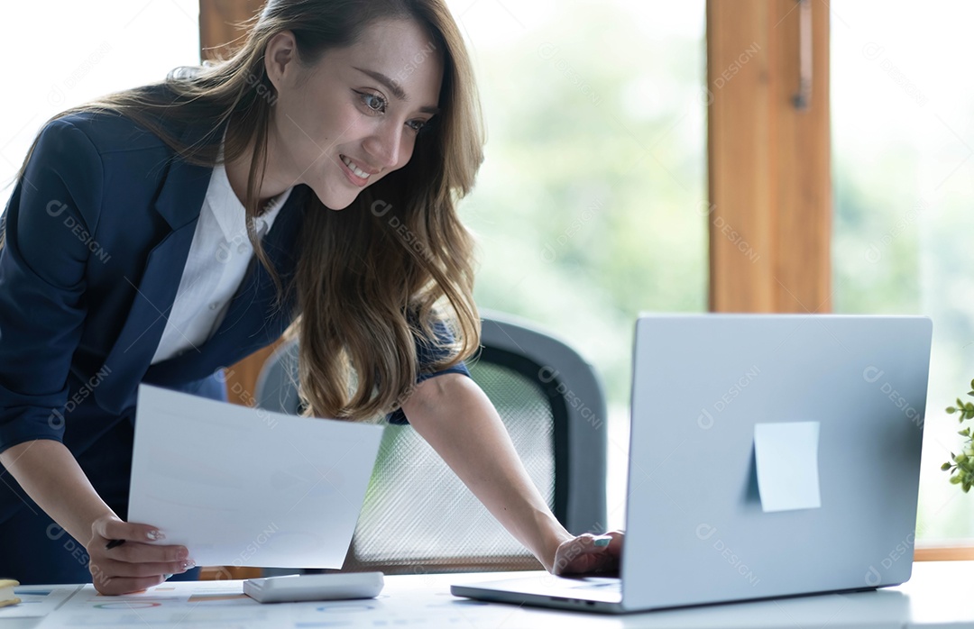 Encantadora mulher asiática trabalhando no escritório usando um laptop