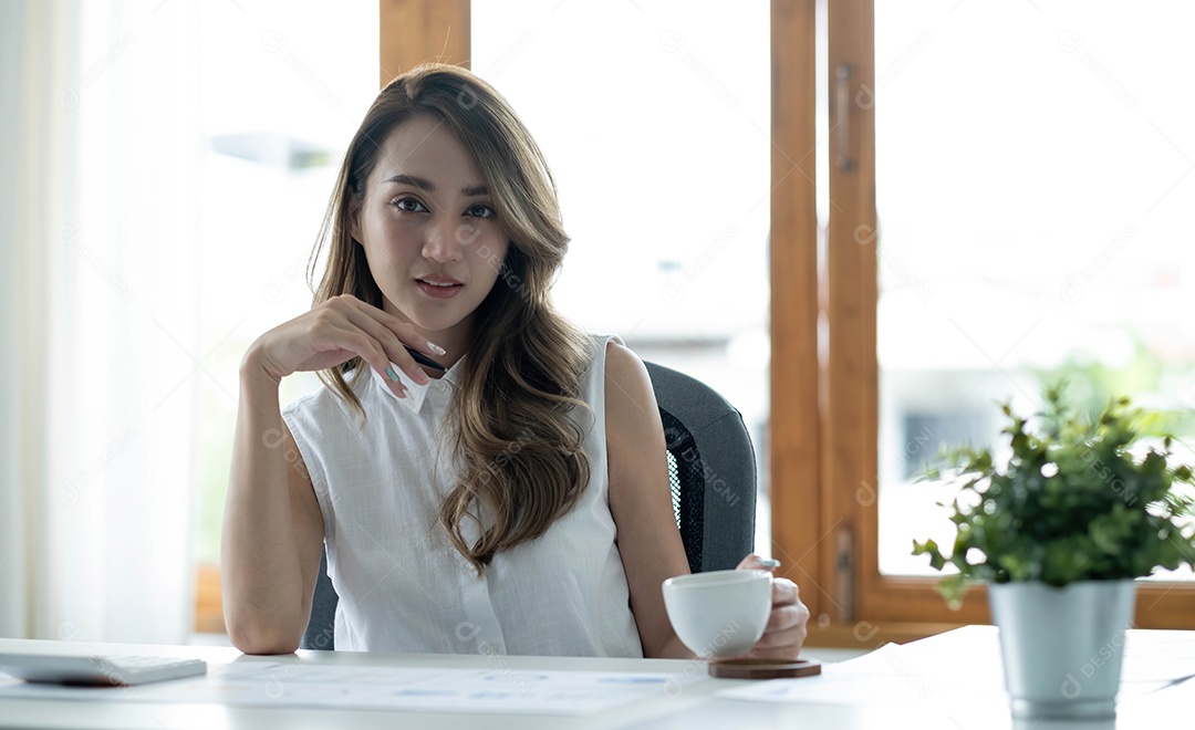 Empresária asiática sorridente segurando uma caneca de café e laptop
