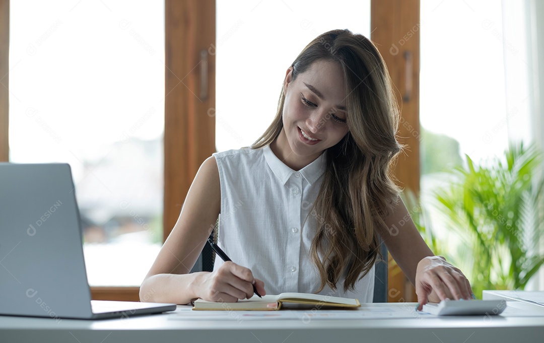 Linda empresária asiática analisa gráficos usando cálculo de laptop
