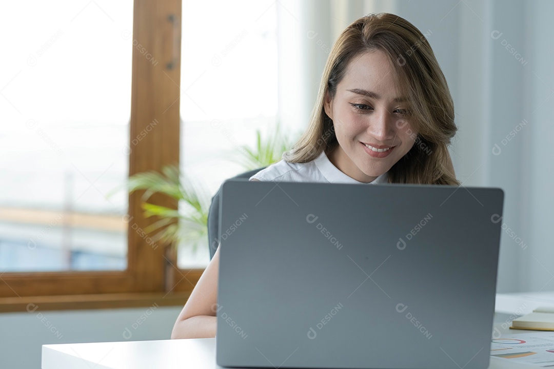 Encantadora mulher asiática trabalhando no escritório usando um laptop