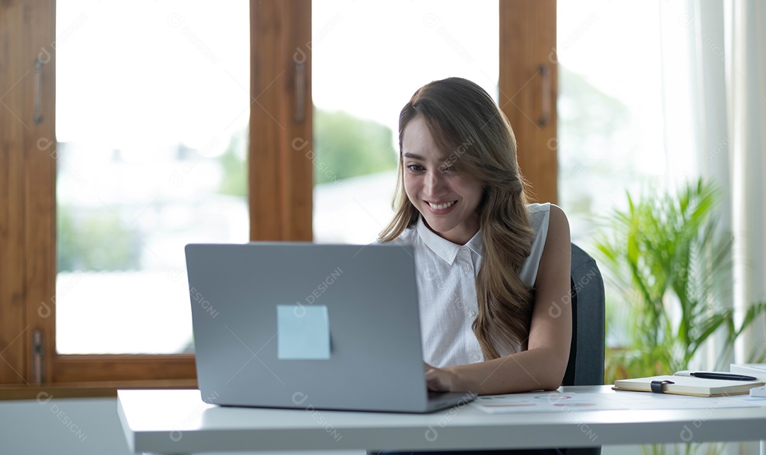 Feliz jovem empresária asiática sentada em seu local de trabalho