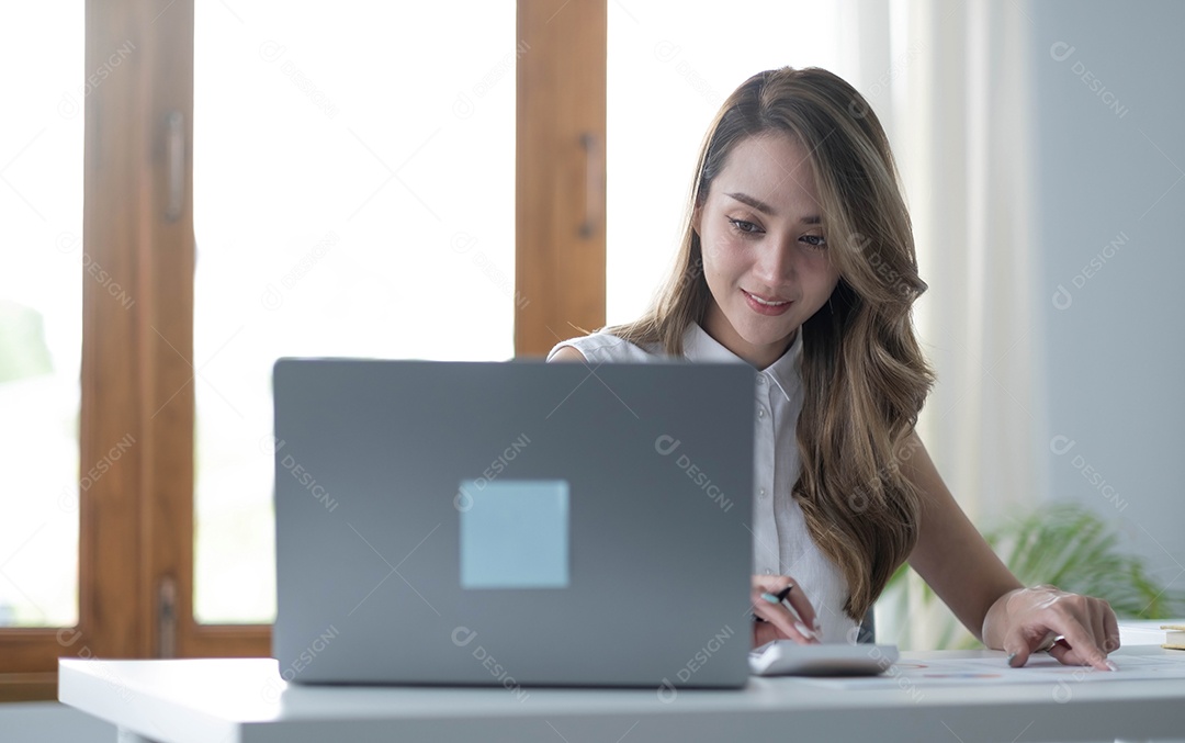 Uma jovem asiática trabalhando no laptop no escritório