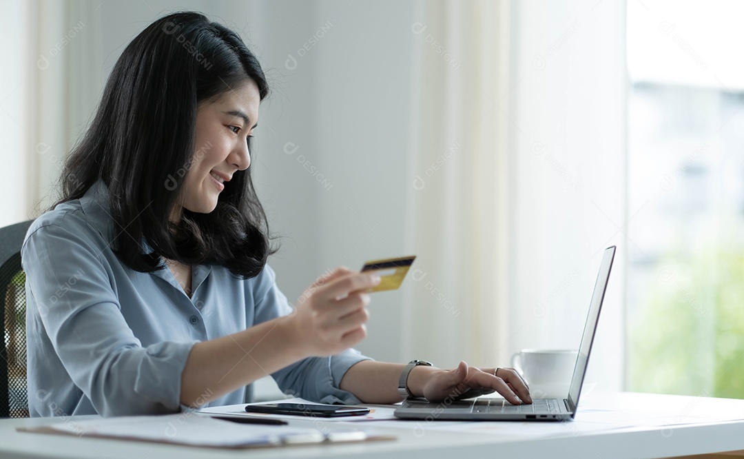 Mulher asiática fazendo compras online segurando cartão de crédito