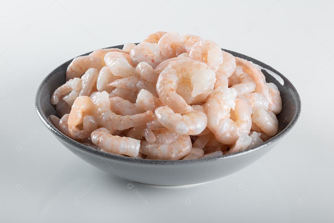 Uma tigela de camarão branco cru fresco descascado com cauda..