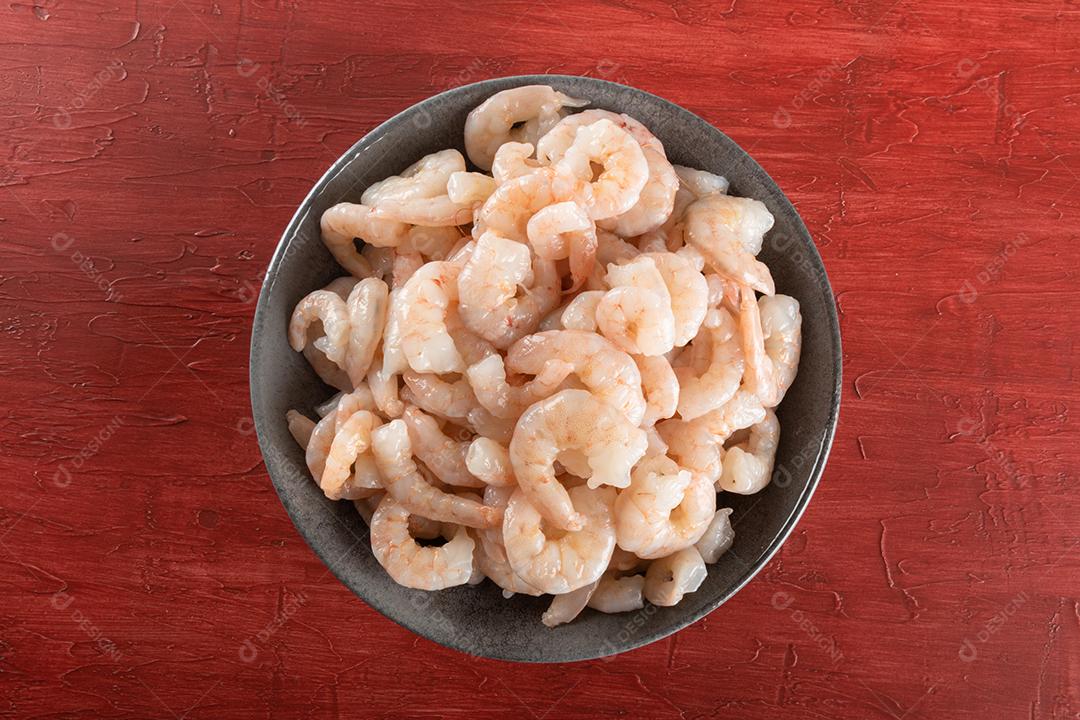 Uma tigela de camarão branco cru fresco descascado com cauda..