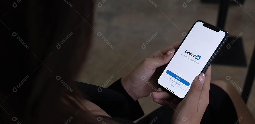 Uma mulher segura o Apple iPhone Xs com o aplicativo LinkedIn na tela.