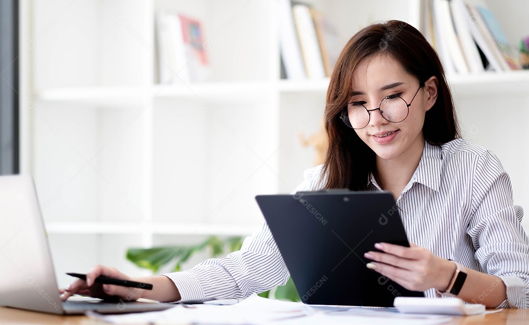 Encantadora empresária asiática sentada trabalhando no laptop no escritório