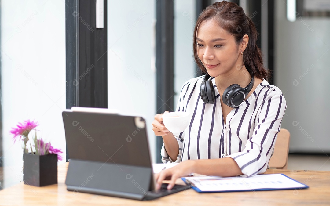 Feliz jovem asiática usando fone de ouvido, comunicando-se com o cliente por meio de uma chamada