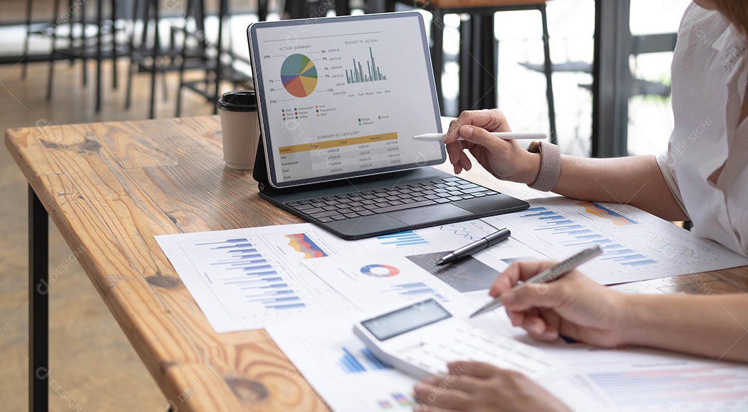 Duas empresárias asiáticas sorridentes de meia-idade discutindo e trabalhando com tablet no escritório.