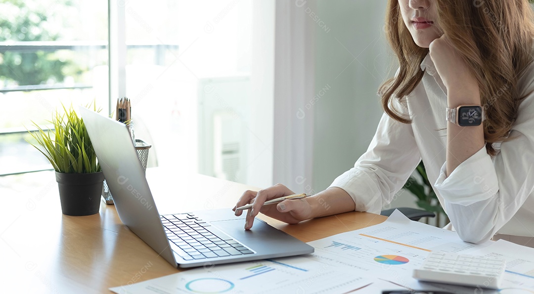 Jovem asiática trabalhando no laptop no escritório