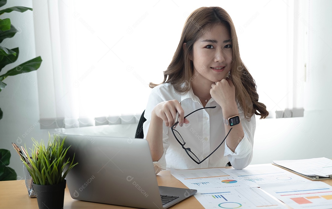 Encantadora mulher asiática trabalhando no escritório usando um laptop