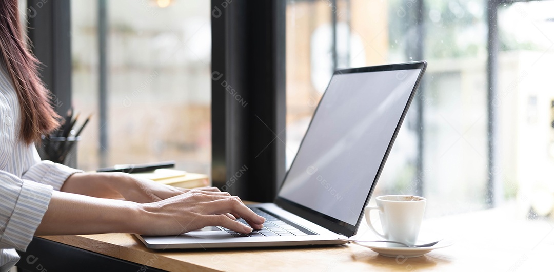 Mão da empresária está digitando em um teclado de laptop com uma tela branca