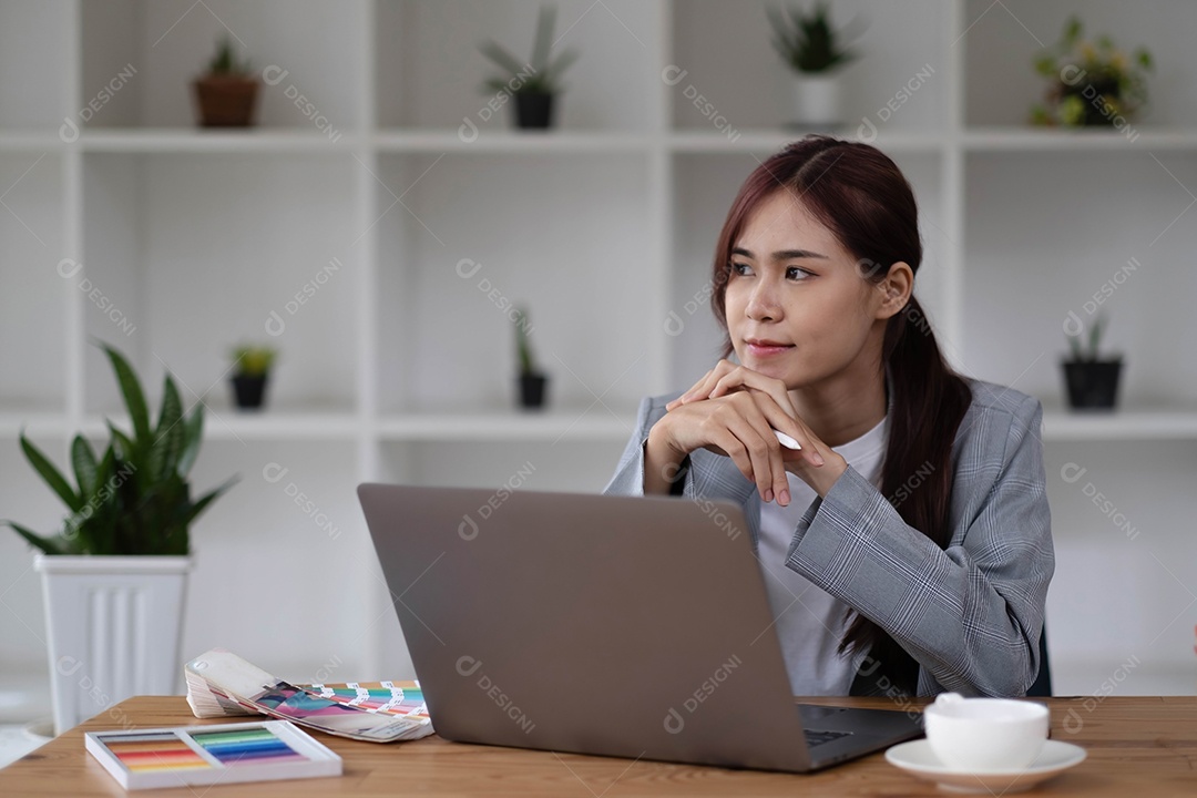 Jovem designer gráfico asiático está trabalhando com amostras de cores