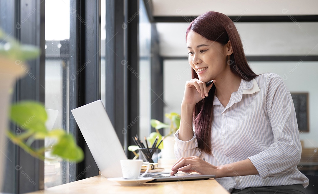 Uma bela jovem asiática sorrindo e olhando para a tela do laptop