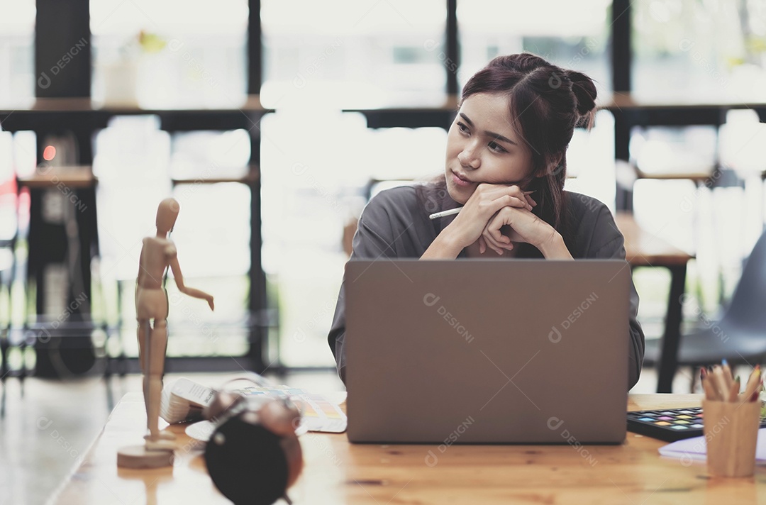 Jovem designer gráfico feminino desenhando em seu projeto com local de trabalho criativo moderno