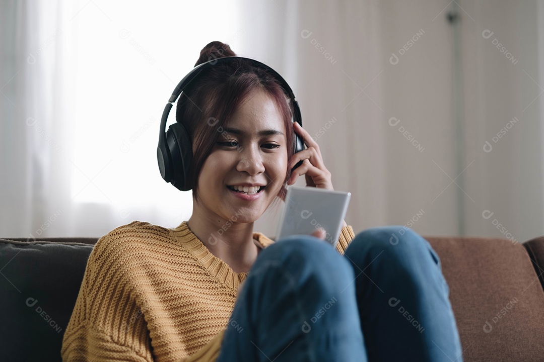 Mulher jovem e atraente no sofá em casa, ela está escutando música