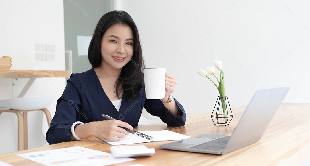 Mulher de negócios asiática jovem sorridente segurando uma caneca de café