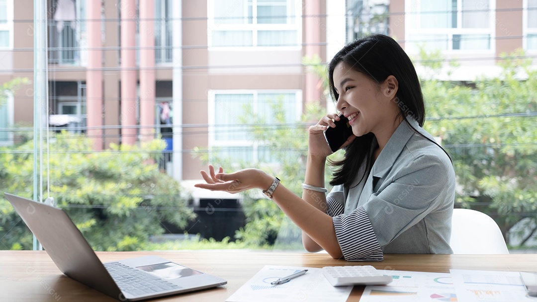Atraente e sorridente jovem empresária asiática relaxando no escritório