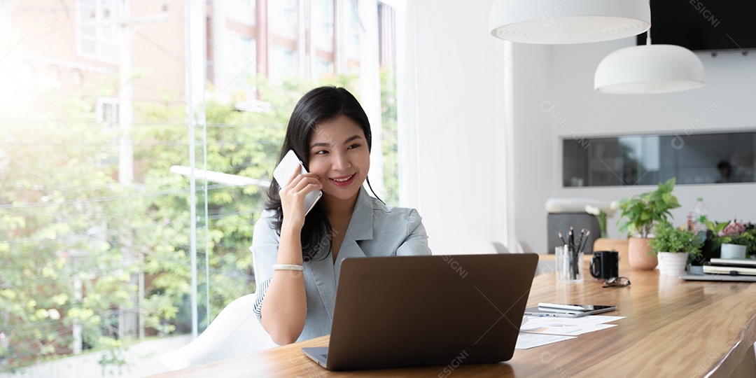 Mulher de negócios asiática tem a alegria de falar ao telefone