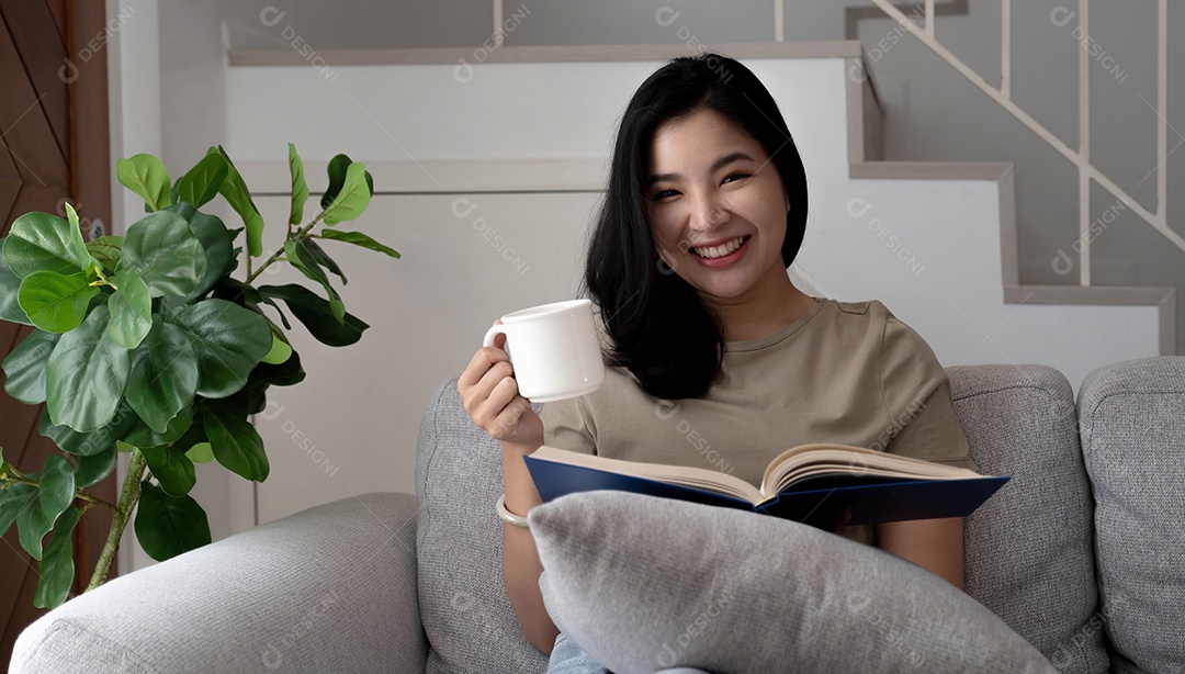 Jovem mulher asiática relaxada e feliz em roupas casuais lendo livro