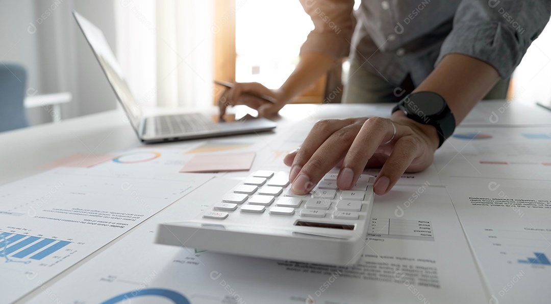 Mão do empresário ou contador segurando o lápis trabalhando na calculadora