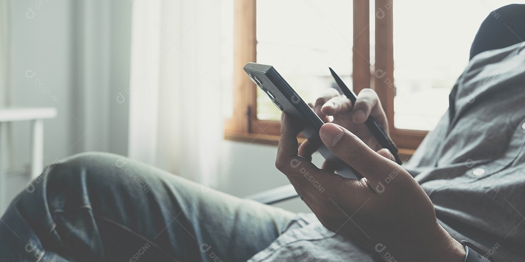 Um homem se senta em uma cadeira em um escritório e usa um smartphone.