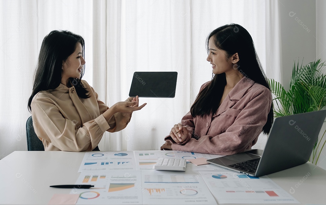 Duas empresárias trabalhando no escritório segurando tablet com tela preta