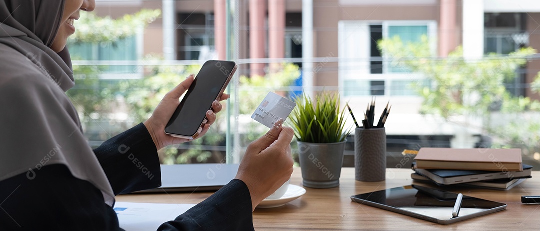 Bela jovem muçulmana com hijab senta-se em sua mesa de escritório